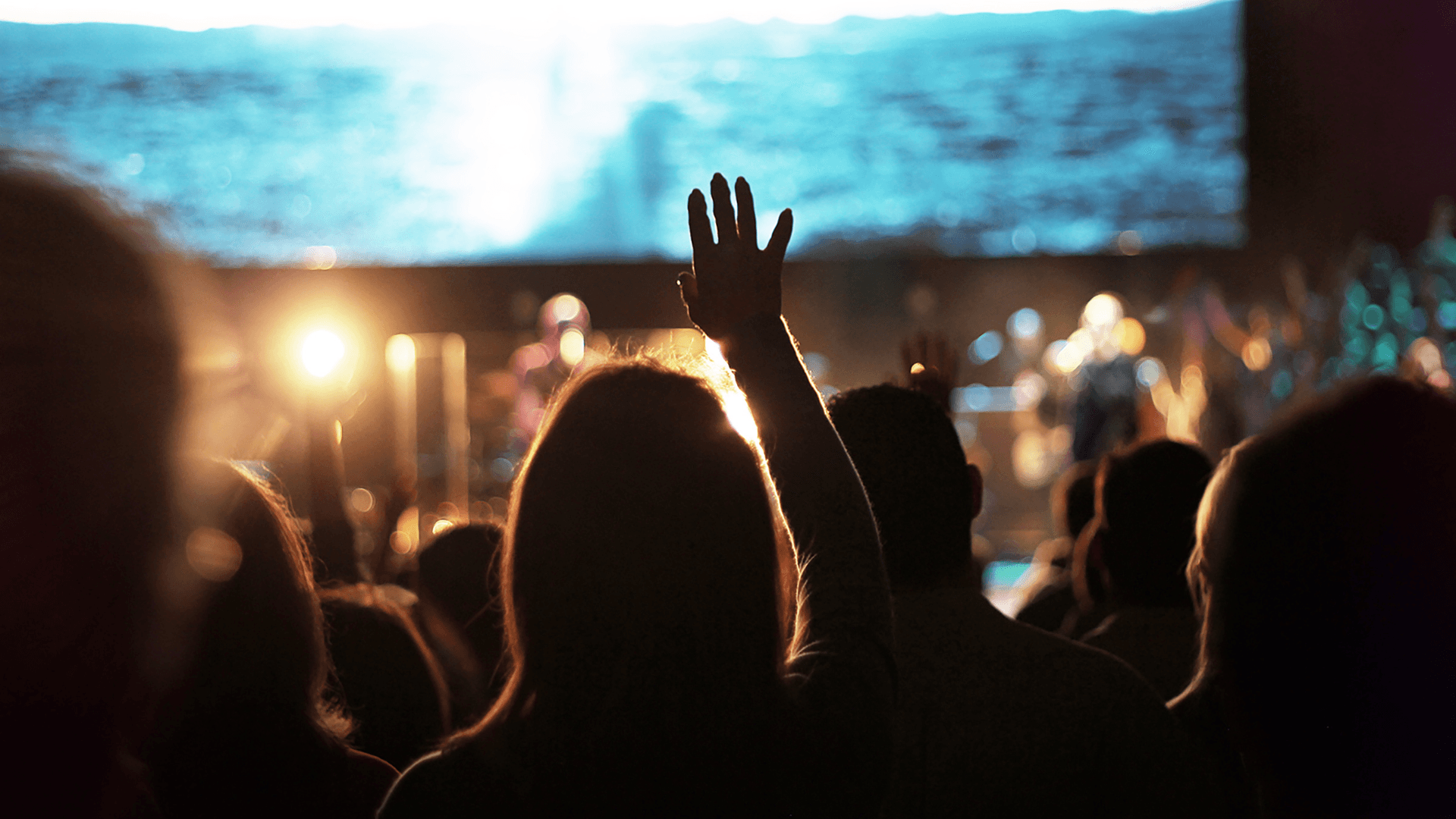 A congregation worshiping together with a hand raised